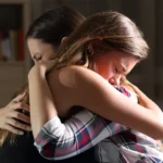 girl-crying-comforted-by-mother