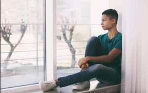 teenage-boy-near-window-sad